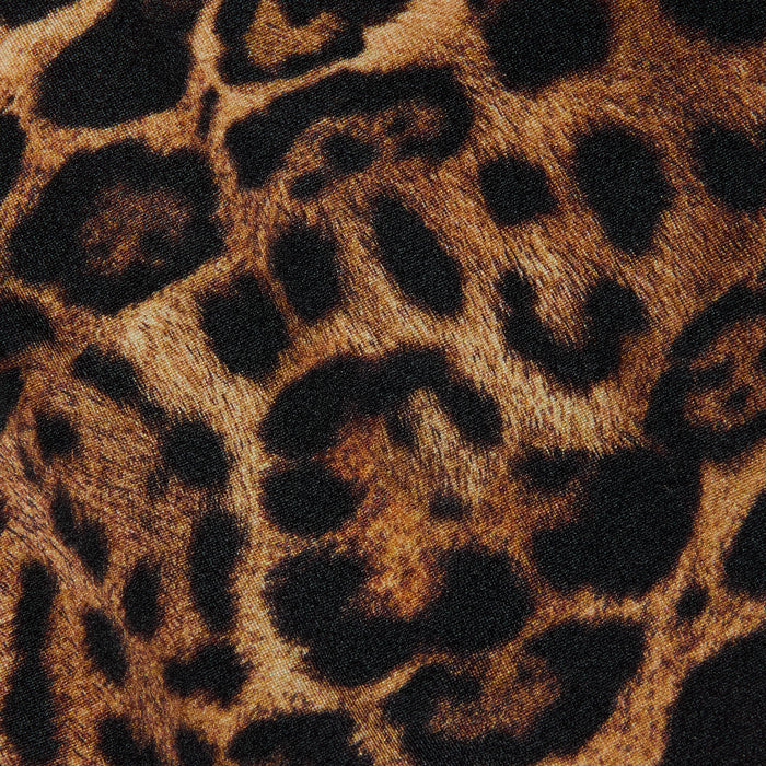 Close-up of the Britt Tie-Side Bikini Bottom fabric featuring a leopard print with black and brown spots on a tan background, mimicking wild animal fur—ideal for resort swimwear or adjustable tie-side styles.