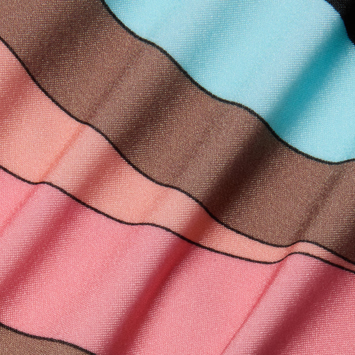 Close-up of the Britt Tie-Side Bikini Bottom fabric, featuring wavy stripes in light blue, brown, and pink tones. The material has a slight sheen and visible texture, with shadowed folds creating a rippled effect reminiscent of an abstract swirl print.