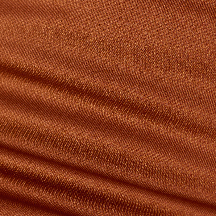 Close-up of rust-colored ribbed fabric displaying horizontal ridges and rich texture, softly lit to highlight the weave and folds—an ideal detail from the Britt Tie-Side Bikini Bottom, designed with adjustable tie sides and moderate coverage.