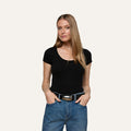 A woman with long, straight blonde hair wears the Brynlee Scoopneck Tee in black and blue jeans, standing with her hands in her pockets against a plain light background.