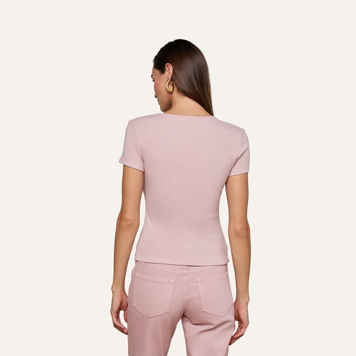 A woman with straight brown hair stands with her back to the camera against a plain, light background, wearing the Brynlee Scoopneck Tee in light pink—a ribbed, stretch cotton-modal top—paired with matching pants.
