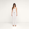 A woman wearing sunglasses, a white sleeveless top, the Cara Low-Rise Bootcut Jean with a belt, and heels stands facing forward against a plain white background.