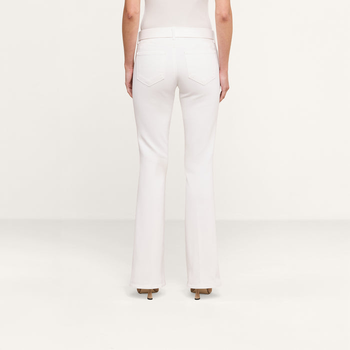 A person is standing on a plain background, shown from the back, wearing the Cara Low-Rise Bootcut Jean in white along with heeled shoes.