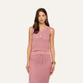 Woman wearing the Carven Pointelle Knit Tank, a sleeveless top with buttons, paired with a matching knit skirt. She stands against a plain light background, epitomizing chic beachwear style.