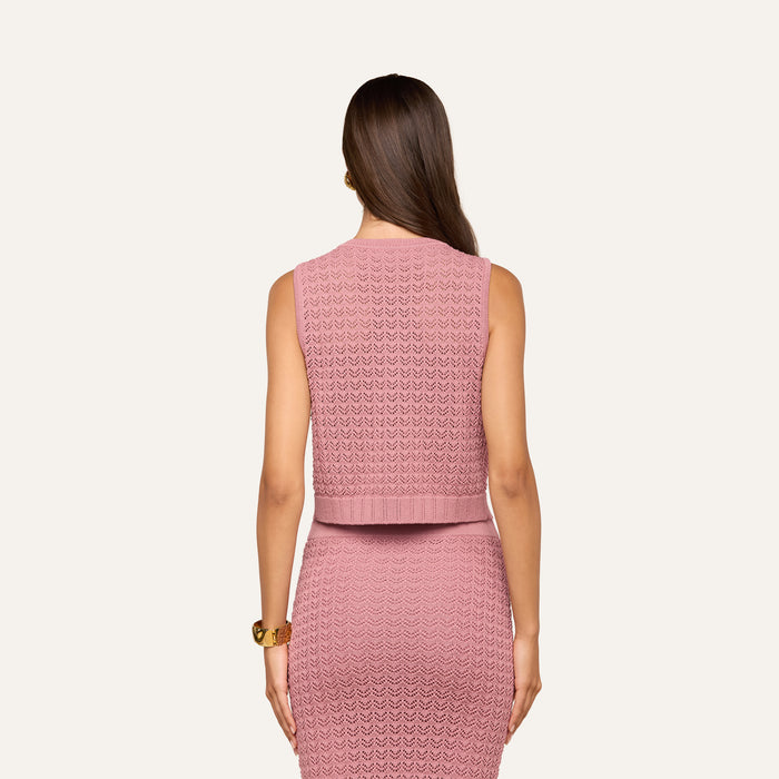 A woman with long brown hair, wearing the Carven Pointelle Knit Tank in pink and a matching skirt, stands with her back to the camera against a plain light background.