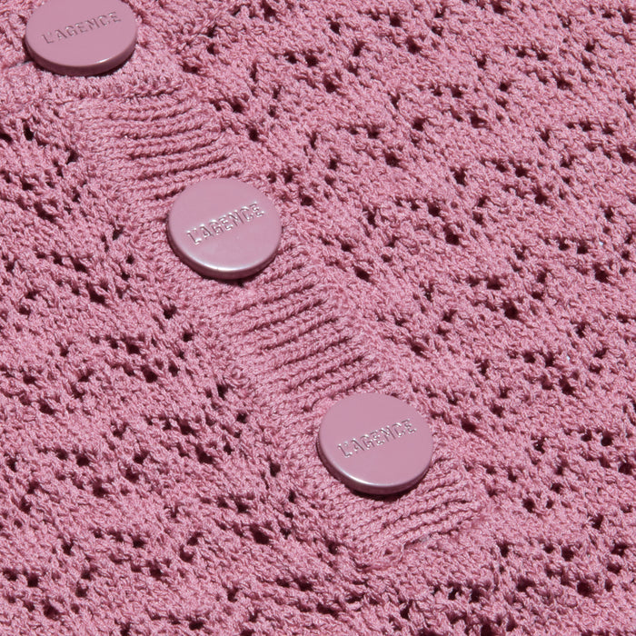 Close-up of the Carven Pointelle Knit Tank’s textured pink pointelle fabric, featuring three round, shiny buttons engraved with LAGENCE, arranged vertically along a subtly ribbed placket.