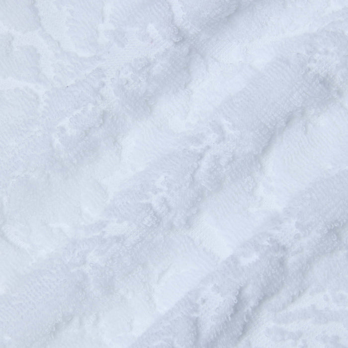 Close-up of soft, white terrycloth fabric with a subtle, wavy pattern and gentle folds, giving the Caterina Cover-Up Robe a plush and cozy appearance reminiscent of luxury loungewear.