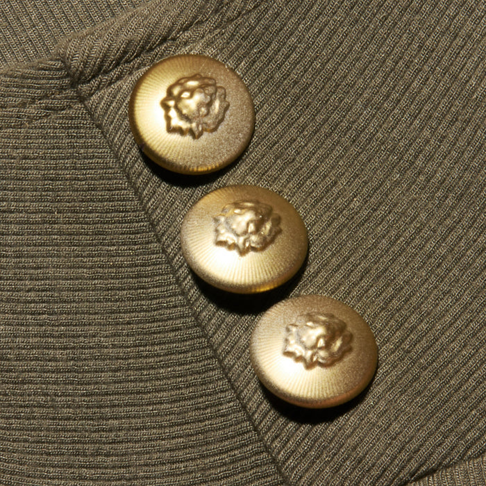 Close-up of three gold buttons with a raised lion design on an ash olive green, ribbed knit fabric—the Ceci Sleeveless Turtleneck.