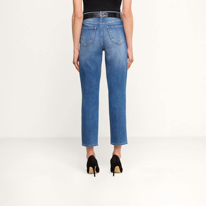 Wearing the Celestia Slim-Leg Jean, black heels, and a black sleeveless top, a person stands facing away from the camera against a plain white background.