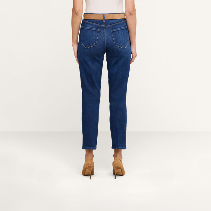 Wearing the Celestia Slim-Leg Jean styled with a beige belt and tan heels, a person stands facing away against a plain light background, showcasing only their lower back, legs, and feet.
