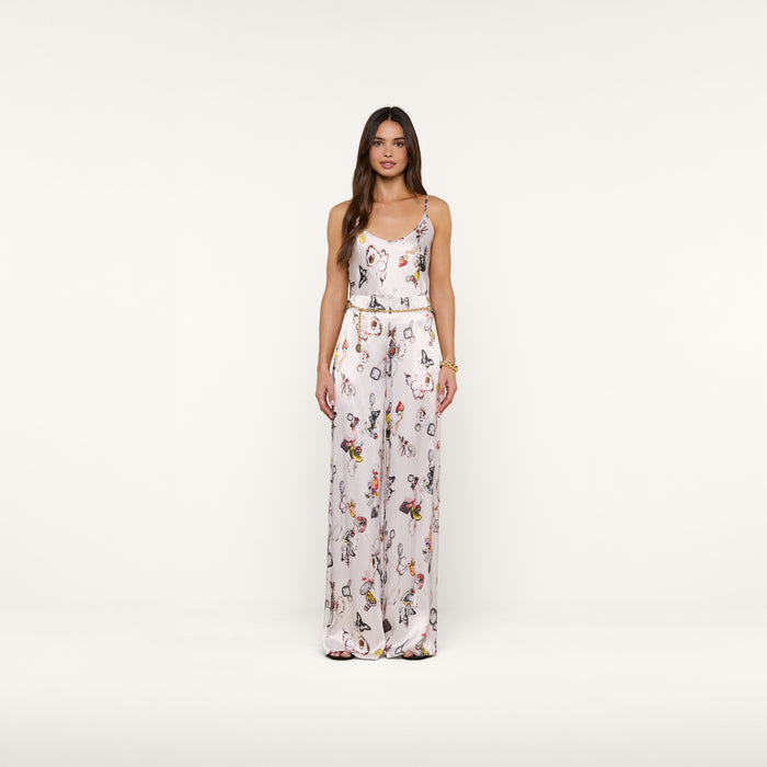 A woman with long brown hair wears the Charmy Satin Camisole, a sleeveless white top featuring a colorful butterfly print, standing against a plain white background.