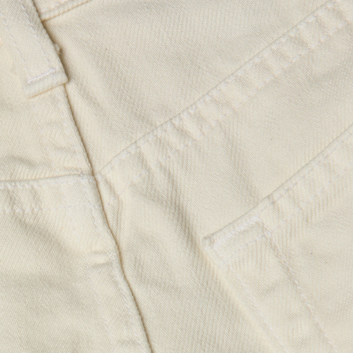 Close-up of cream-colored all-cotton denim fabric showing stitching, a seam, and part of the Clark Distressed Jean Short pocket.