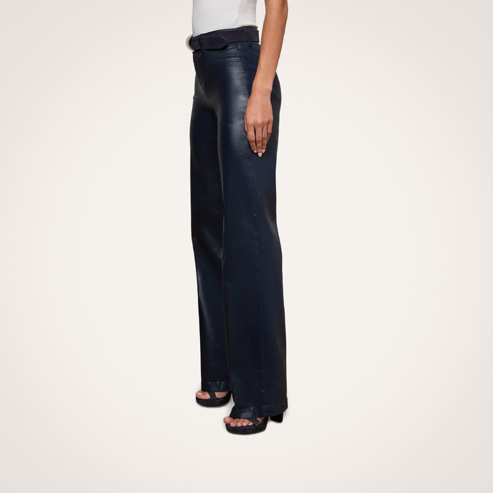 A person wearing the Clayton Coated Wide-Leg Jean in black, paired with black platform sandals, shown from the waist down against a plain white background.