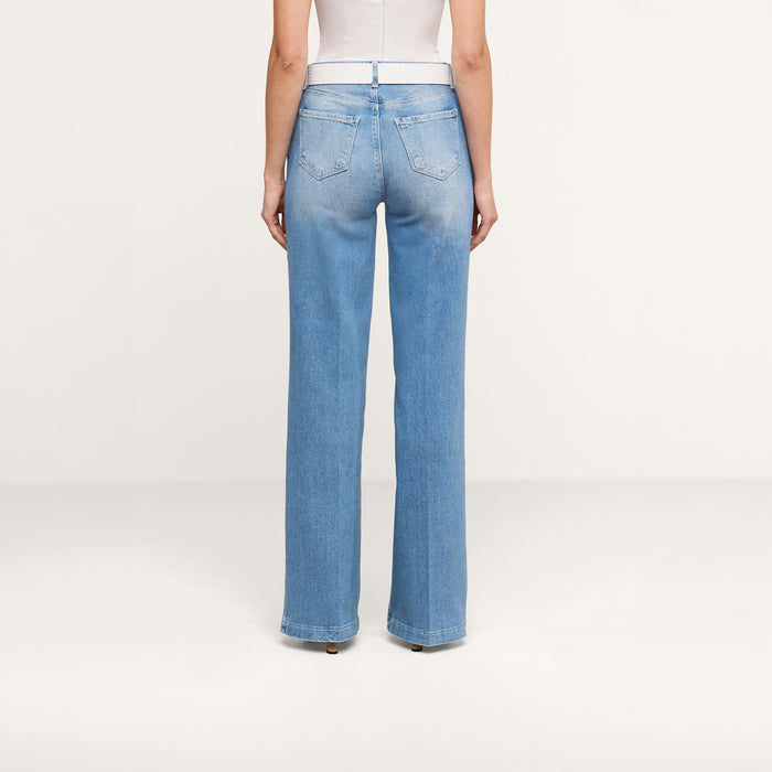 A person stands facing away, wearing the Clayton Wide-Leg Jean in light blue high-rise denim with a white top against a plain white background.