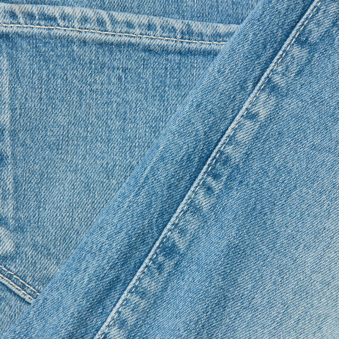 Close-up of light blue denim fabric with pocket and seam details, highlighting the texture and stitching characteristic of the Clayton Wide-Leg Jean.