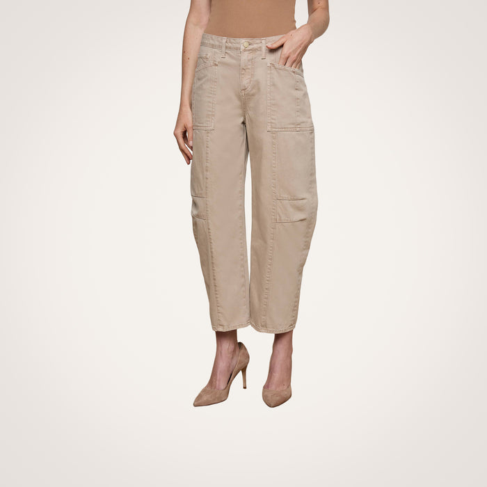A person models the Cody Cropped Barrel-Leg Jean, featuring patch pockets and a beige hue, paired with nude heels. They stand against a plain white background, with only their lower body visible.