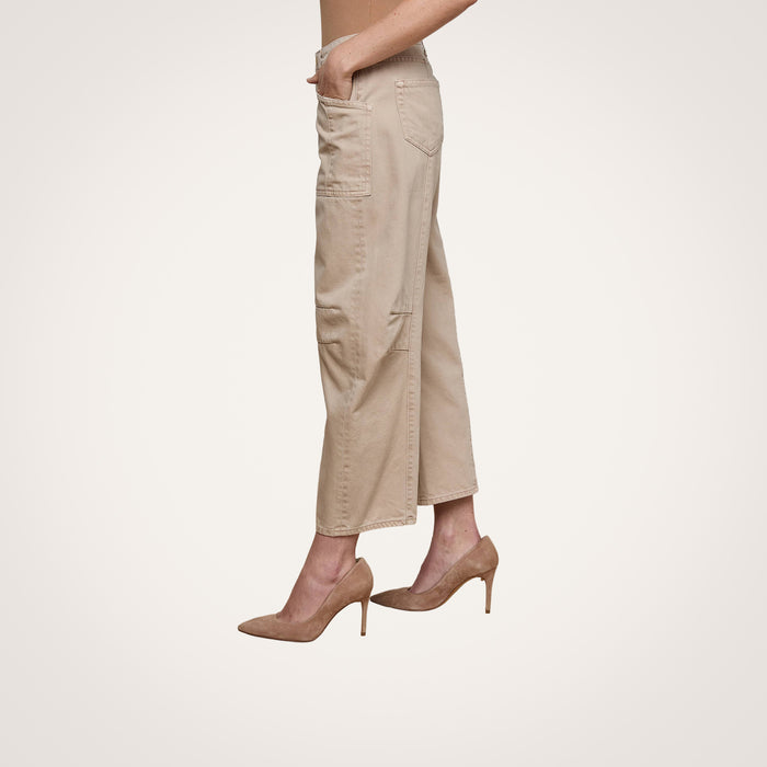 A person, shown from the waist down in profile against a plain white background, wears Cody Cropped Barrel-Leg Jeans with patch pockets and tan high-heeled shoes.