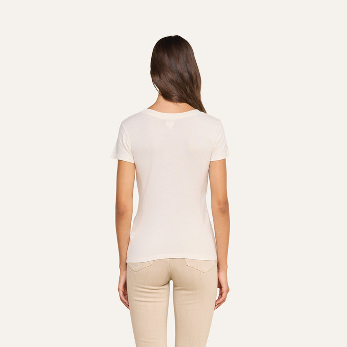 A woman with long brown hair stands facing away, wearing the Cory Cotton Scoopneck Tee and matching pants against a plain, light background.