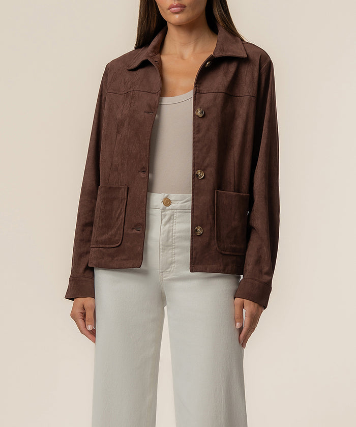Chocolate brown faux suede jacket with collar, button front, and patch pockets worn over white top.