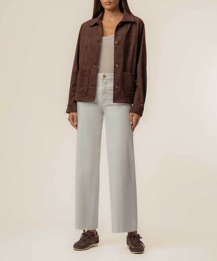 Chocolate brown faux suede jacket with collar, button front, and patch pockets worn over cream top and pants.