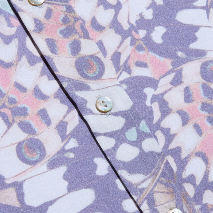 Close-up of the Dani Silk Blouse, showcasing its button-down design in silk with a pastel butterfly wing print in purple, pink, and blue tones, accented by white buttons along the fabric.