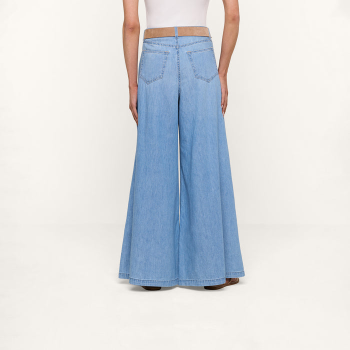 A person is shown from the back against a plain white background, wearing the Dariela Wide-Leg Jean in light blue with a high-rise, ultra wide-leg fit, paired with a white top.