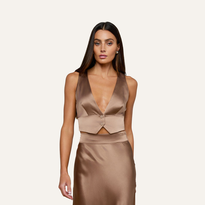 A woman wearing the Devony Silk Vest with a plunging neckline and matching satin skirt stands against a plain light background, looking directly ahead with a neutral expression.