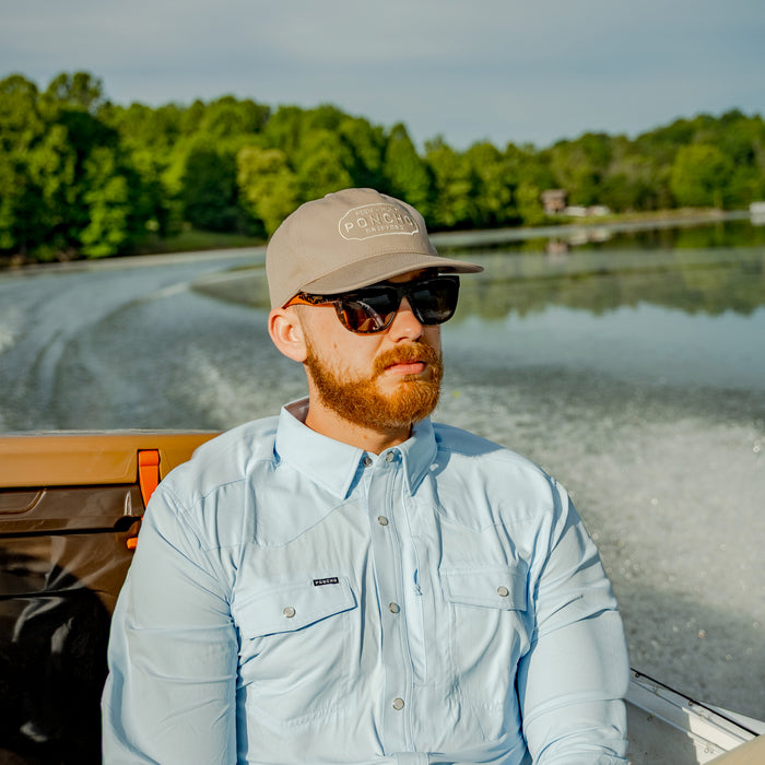 Man riding in boat wearing a tan ball cap