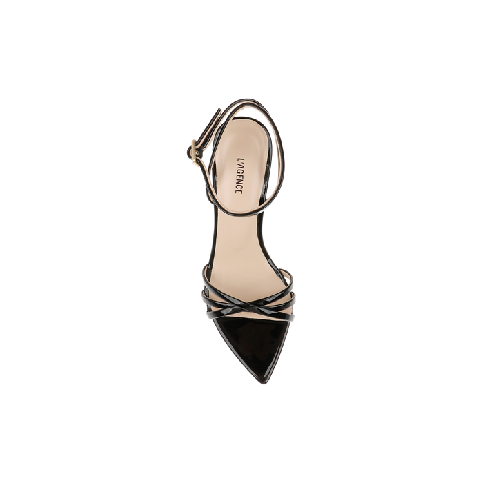 The Dua Leather Sandal, crafted from black patent leather and featuring a pointed toe, slender ankle strap, and stiletto heel, is shown from above against a white background.