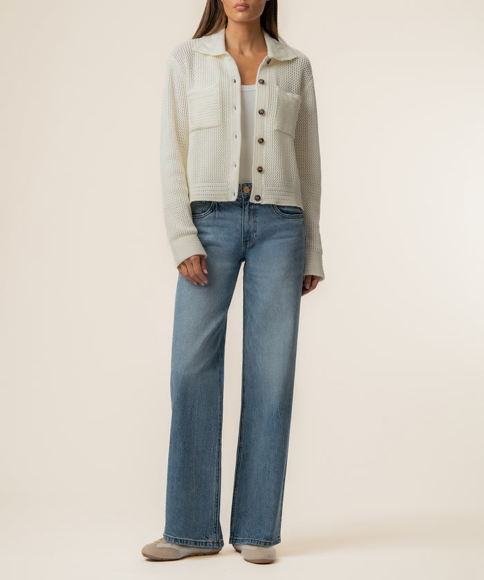 Cream knit cardigan with collar and button front worn over white tank top and medium wash straight-leg jeans.