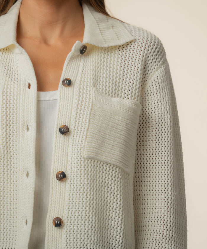 Cream knit cardigan jacket with tortoiseshell buttons, textured knit fabric, and patch pocket detail.