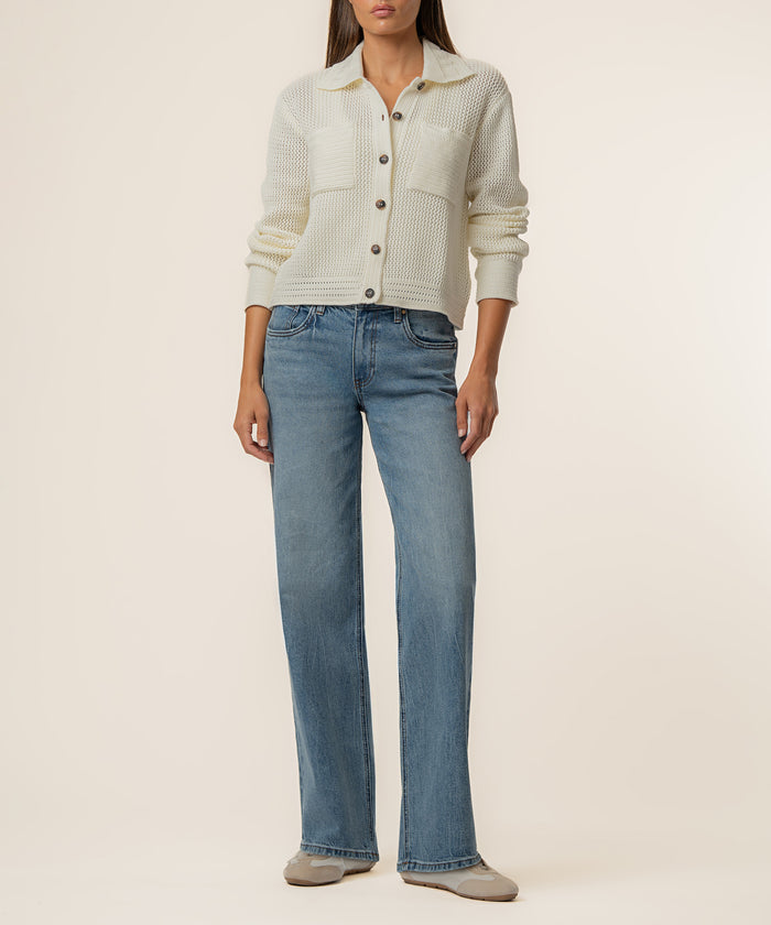 Cream knit cardigan with textured fabric and button front, styled with blue jeans.