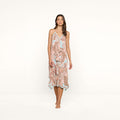 A woman stands barefoot against a white background, wearing the Elise Cover-Up Dress, which features a paisley print, halter neckline, V-neckline, and a flowy midi silhouette.