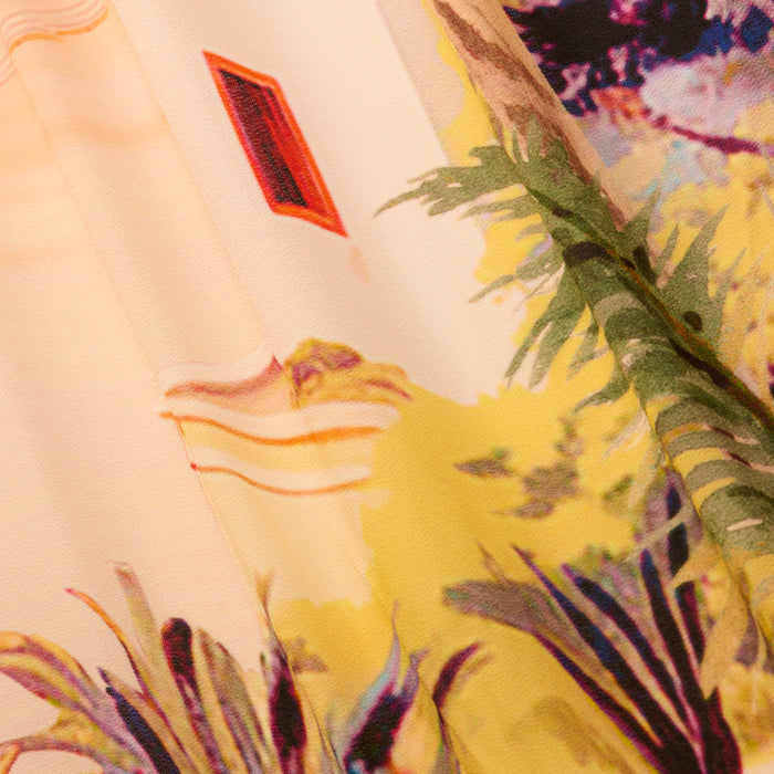 The Elise Cover-Up Dress features a colorful fabric with a scenic postcard print of tropical plants, vibrant yellow and green foliage, and a red-framed window, evoking a sunny outdoor atmosphere.