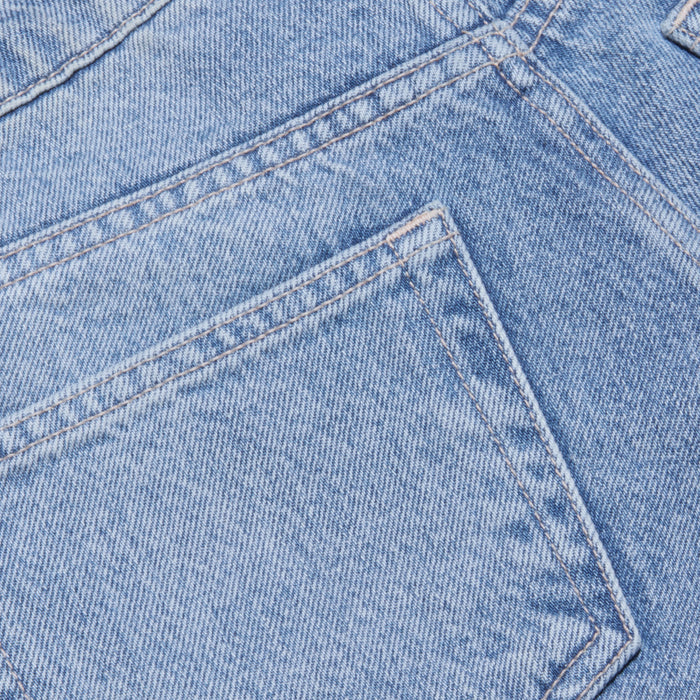 Close-up of light blue all-cotton denim fabric showing a pocket and visible stitching details on the Elise Jean Bermuda Short.