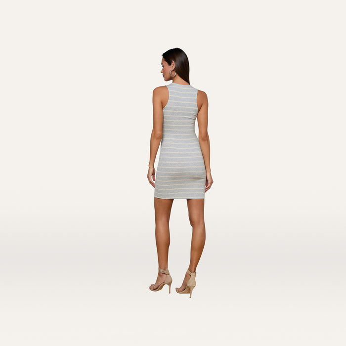 A woman stands facing away against a plain white background, showcasing the back of the Ellis Tank Dress—a sleeveless, gray striped mini dress with a racerback silhouette—paired with nude heels.