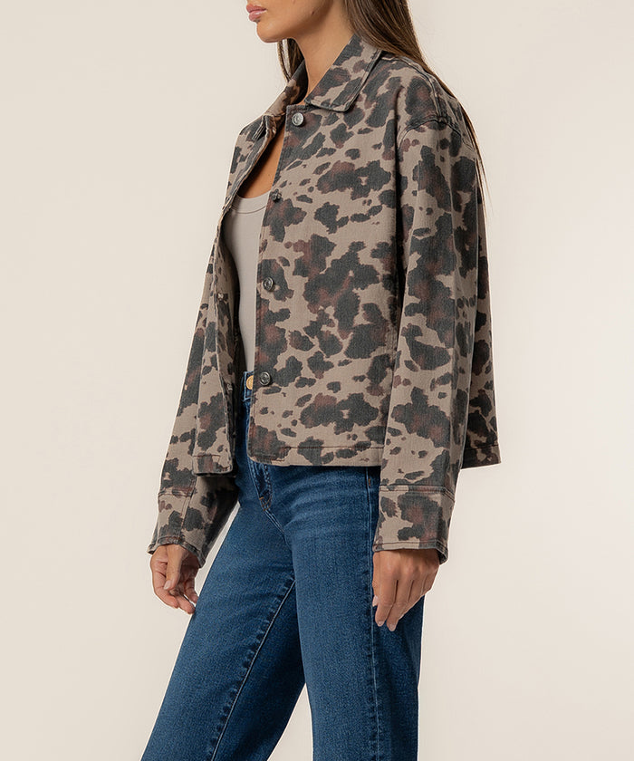 Woman wearing taupe denim jacket with leopard print pattern and button front over blue jeans.