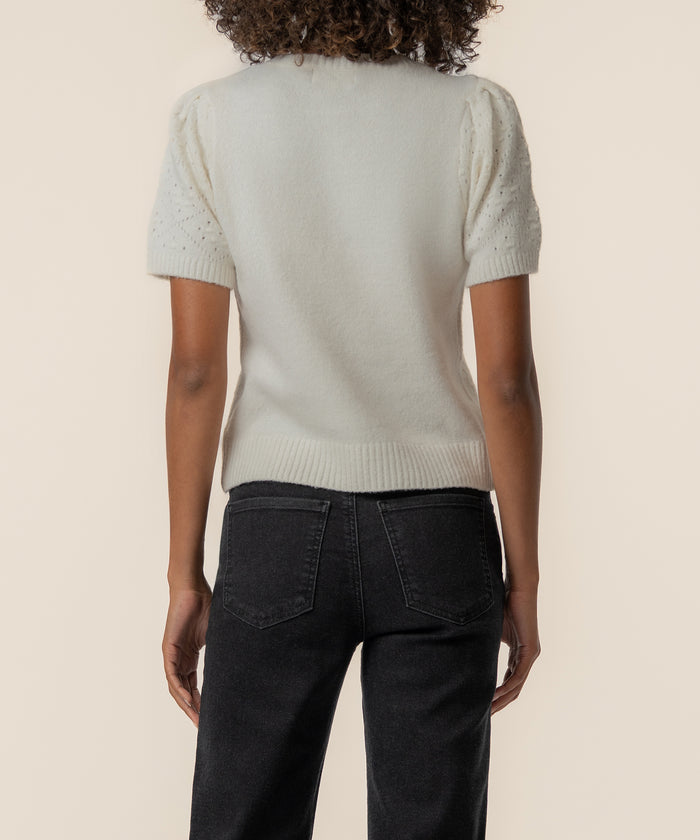 Cream short-sleeve sweater with textured sleeves, back view on model wearing black jeans.