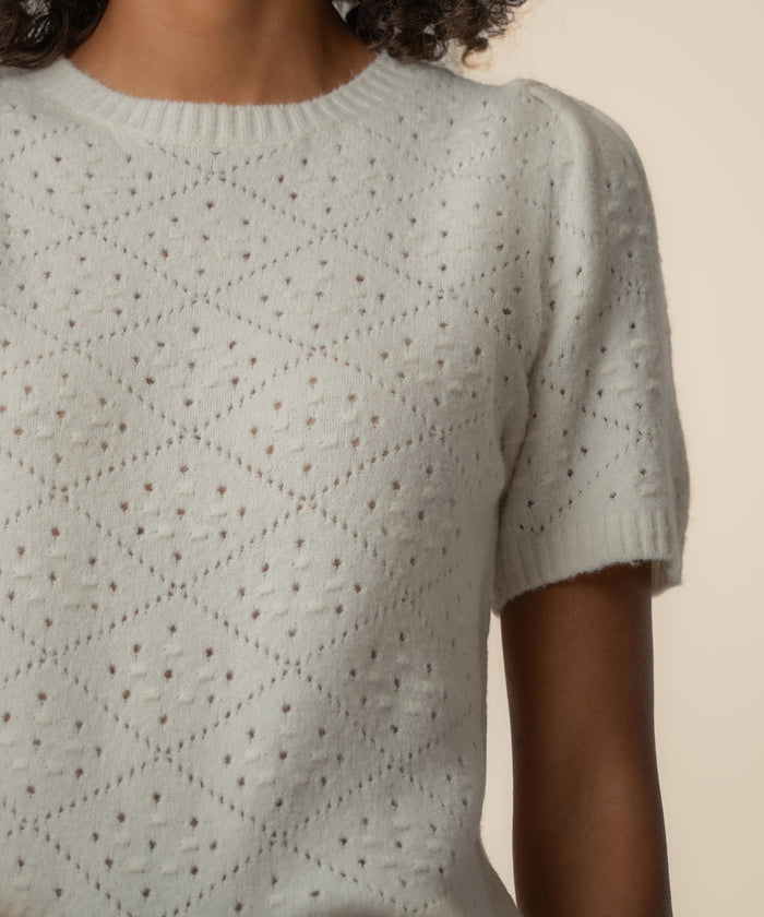 Cream short-sleeve sweater with small dotted texture and quilted diamond pattern throughout.