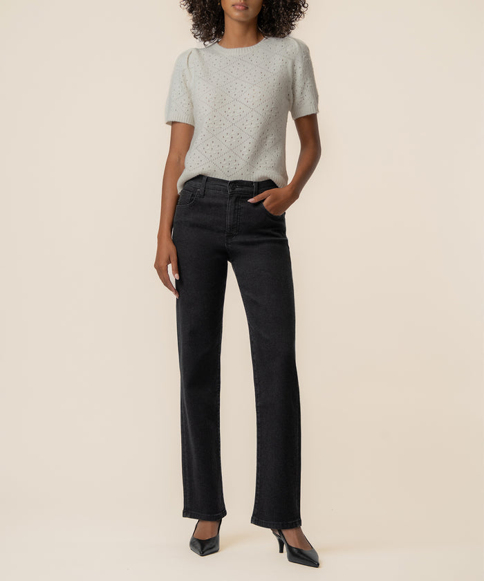 Cream knit sweater with speckled texture and short sleeves paired with black straight-leg jeans.