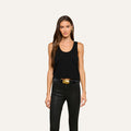 Woman with long brown hair wears the Filou Cashmere Tank, styled with black leather pants and a black belt featuring a large gold buckle, standing against a plain light background. Her look captures luxurious layering—ideal for an elevated, modern wardrobe.
