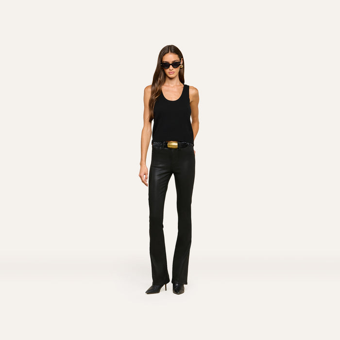 A woman wearing the Filou Cashmere Tank in black, paired with black leather pants, a black belt with a gold buckle, black pointed boots, and sunglasses stands against a plain white background.