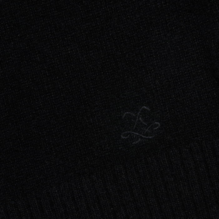 A close-up of the Filou Cashmere Tank in black, showcasing its textured fabric and a subtle embroidered design with flowing, intersecting lines near the center—an ideal detail for luxury layering or building your sweater capsule.