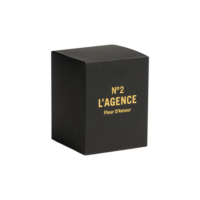 A black box with gold text reading N°2 LAGENCE Fleur D’Amour on the front, set against a plain white background, evokes the luxurious essence of Fleur D’Amour and hand-poured candles crafted from soy-blend wax.