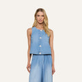 A woman stands against a plain, light background, wearing the Foster Top—a sleeveless piece crafted from featherweight denim—paired with matching wide-leg denim pants.