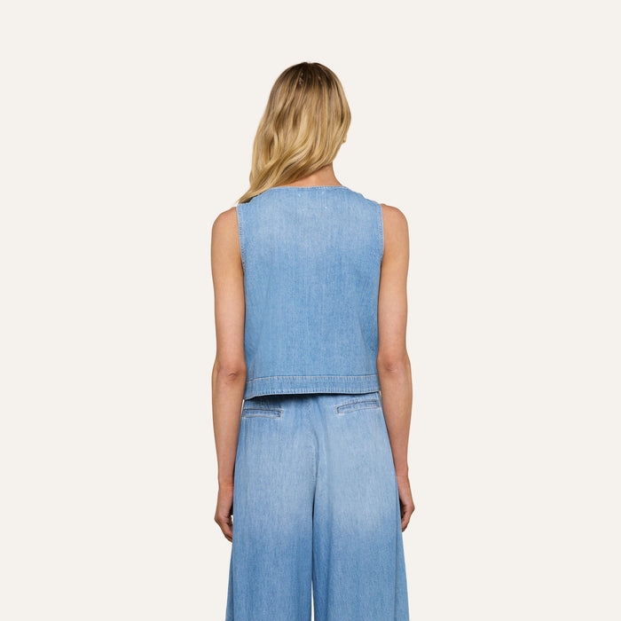 Person with long blonde hair shown from the back, wearing the Foster Top — a sleeveless featherweight denim vest — and matching high-waisted wide-leg jeans with an A-line silhouette against a plain background.