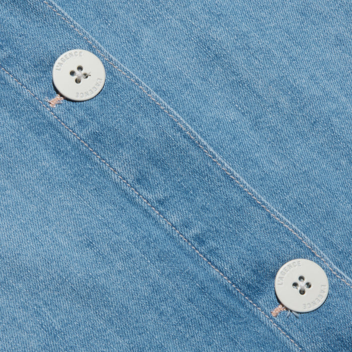 Close-up of the Foster Top’s featherweight denim, featuring two white four-hole buttons with faint text along the edges, sewn diagonally along a seam.