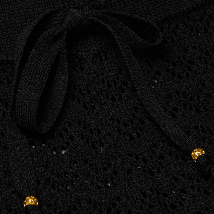Close-up of the Gaelle Pointelle Knit Pant in black, featuring a pointelle knit fabric and a tied drawstring waist finished with small gold-colored beads at the ends.
