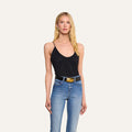 A woman with long blonde hair is wearing the Gelina Mesh Bodysuit with adjustable straps, paired with blue jeans, a black belt featuring a gold buckle, and gold earrings, standing against a plain light background.