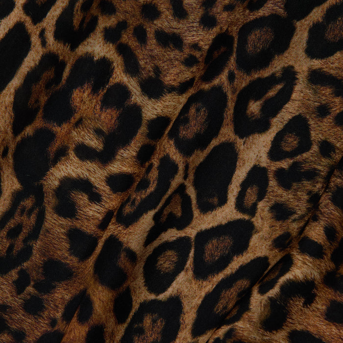 Close-up of the Geraldine Cover-Up Pant, showcasing leopard print fabric with black and dark brown spots on a tan background, visible folds, and a soft texture—ideal for resort wear or as wide leg pull-on pants.
